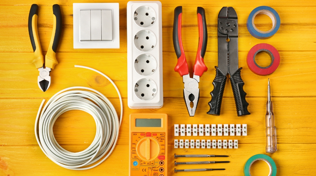 YH Akademins yrkesutbildning: Elektriker-verktyg och utrustning på gult bord.