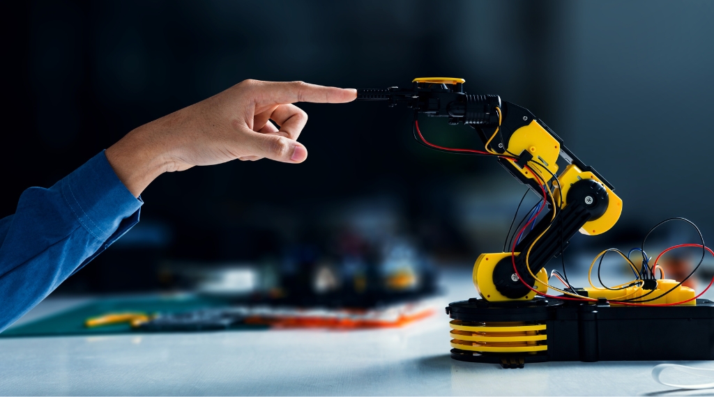YH Akademins yrkesutbildning: hand styr robotarm i tekniklaboratorium.