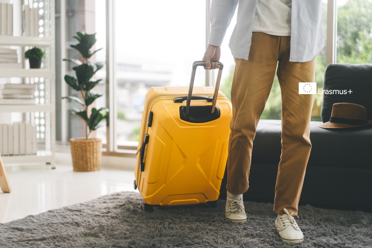 Student på YH Akademin med gul resväska i ljus lägenhet redo för studier utomlands.