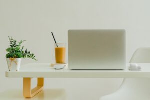 Skrivbord med en dator och ett glas juice.