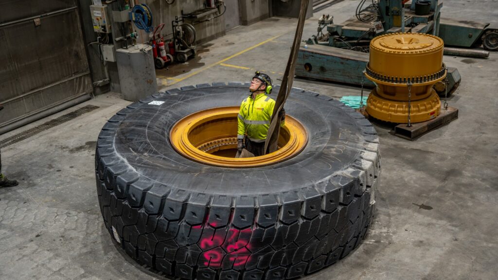 En arbetare i en gul skyddsjacka står inne i ett stort industridäck i en verkstadsmiljö.