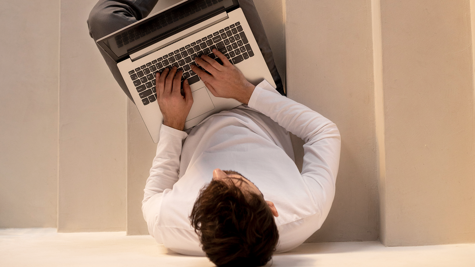 Person sitter på en trappa och skriver på en laptop samtidigt som hen arbetar med sin korta kurser ansökan, sett ovanifrån.