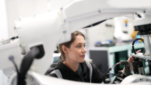 En kvinna arbetar på en stor robotmaskin i ett högteknologiskt laboratorium.