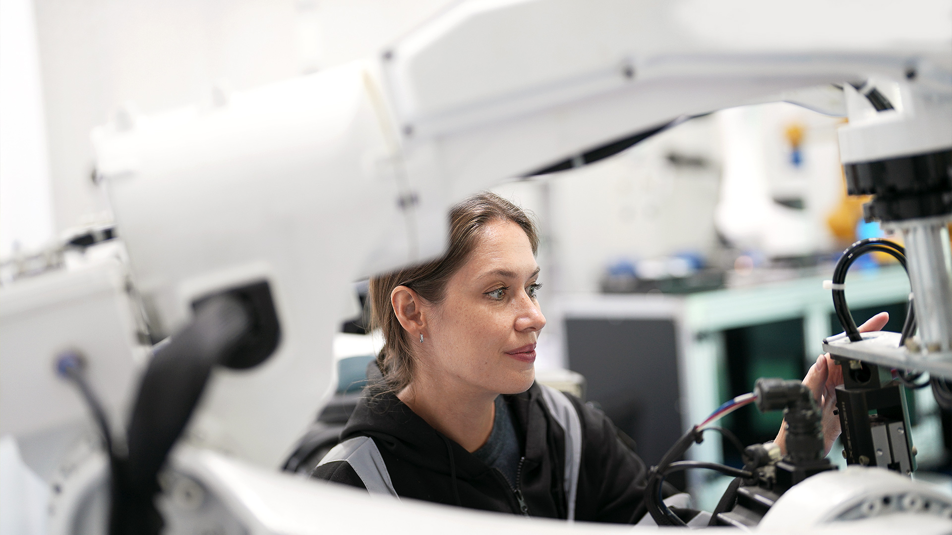 En kvinna arbetar på en stor robotmaskin i ett högteknologiskt laboratorium.