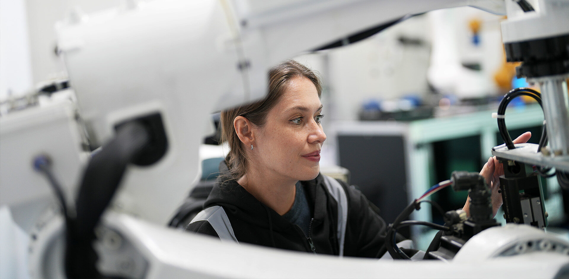 En kvinna arbetar på en stor robotmaskin i ett högteknologiskt laboratorium.