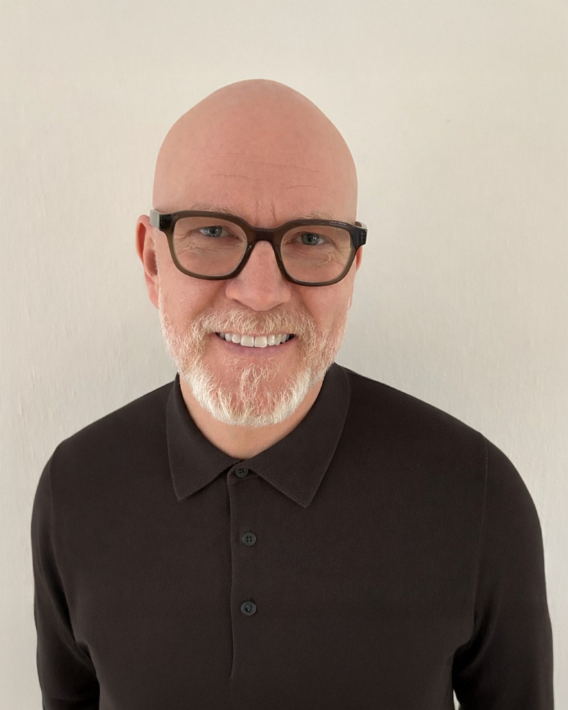 Skallig man med glasögon, skägg och en svart skjorta med krage, ler mot en vanlig ljus bakgrund. RecoLab är med i ledningsgruppen - Dagvatteningenjör.