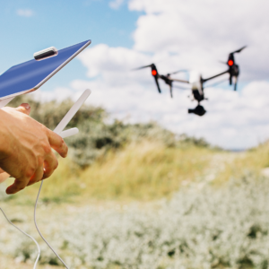 En person opererar en drönare med fjärrkontroll och surfplatta utomhus under blå himmel - idealisk utbildning för Företagsutbildning - UAS fjärrpilot och operatör inom kategori specifik.