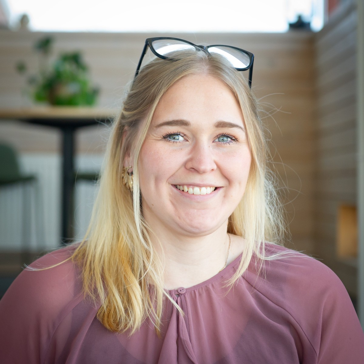 En leende blond kvinna med glasögon på huvudet – från kulturbranschen till tunga maskiner.